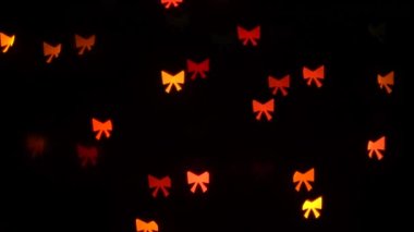 Siyah arka plandaki dekoratif çelenk üzerinde yanıp sönen bokeh ışıkları. Göz kırpan yeşil, mavi, kırmızı ve sarı. Kavram: Noel, Yeni Yıl, Tatil, Doğum Günü.