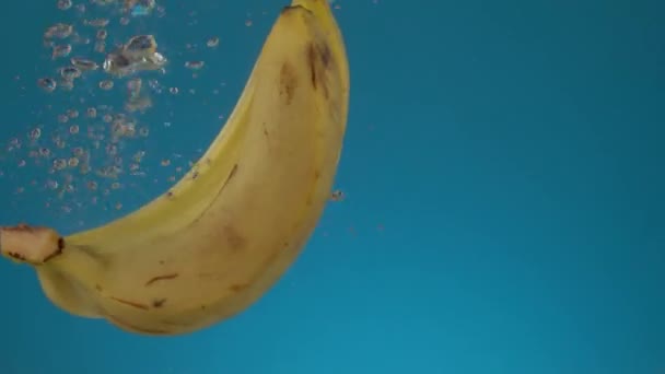 Tres Plátanos Amarillos Jugosos Frescos Cámara Lenta Caen Agua Con — Vídeo de stock