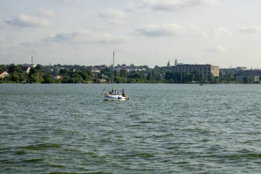Arka planda mavi gökyüzünde beyaz yat denizde yüzüyor. Maceralı bir tekne gezisine çıkıyorum. Açık denizde yelkenli tekne.