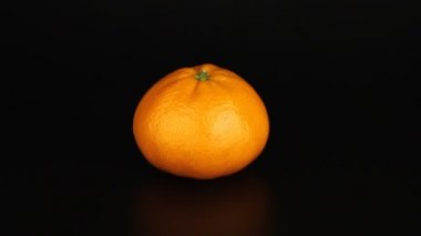 Bütün bir mandarin siyah bir arkaplanda döner. Sağlıklı vitaminler yakın plan..