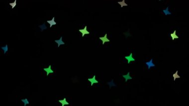 Siyah arka planda dekoratif çelenk üzerinde parlayan bokeh ışıkları. Göz kırpan yeşil, mavi, kırmızı ve sarı. Kavram: Noel, Yeni Yıl, Tatil.