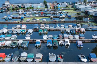 Birçok renkli sürat tekneleri rıhtıma park etti. Su nakli için yer. Sürat tekneleri için garaj sistemi. Marina gemi istasyonuna demirlemiş. Nehir kıyısındaki turizm beldesi.
