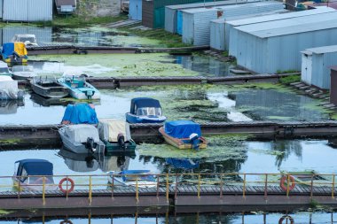 Birçok renkli sürat tekneleri rıhtıma park etti. Su nakli için yer. Sürat tekneleri için garaj sistemi. Marina gemi istasyonuna demirlemiş. Nehir kıyısındaki turizm beldesi.