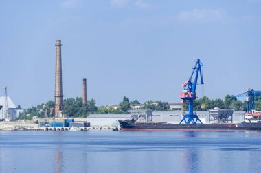 Big port cranes on the river. Extraction and transportation sand. Harbor crane loads water resources into the barge. Special equipment and water transport. River port. Industrial city.