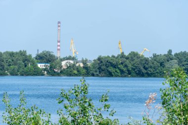 Big port cranes on the river. Extraction and transportation sand. Harbor crane loads water resources. Special equipment and water transport. River port. Industrial city.