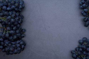Beton bir arka planda kırmızı üzüm kümeleri bulunur. Yakın plan. Üst manzara, düz yatış. Eklenecek bir yer var. Menü sunumu, reklam afişi ve şarap listesi için mükemmel