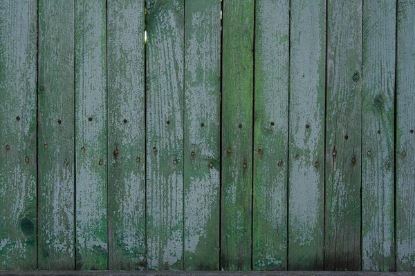 Ahşap çit dokusu. Çit yeşile boyanmış. Eski bir çitin boyasını soyuyordu. Eski ahşap doku. Fotoğraf bir fotofon, bir doku olarak kullanılabilir.