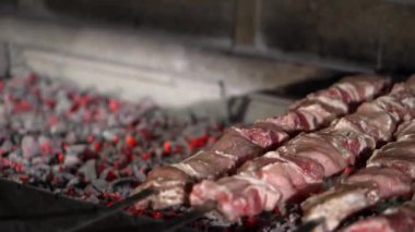 Aşçı ızgaraya et şişini koyar. Videoda kıvrımlı barbeküden yükselen közler ve dumanlar var. Yakın çekim, yavaş çekim