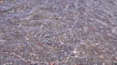 a mountain stream with clean drinking water flows over beautiful multi-colored stones. close-up. beautiful glare from the sun on the water surface