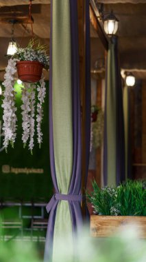 Lokantanın iç kısımlarının ayrıntıları. Tenceredeki güzel bir çiçek ahşap bir direğe asılı. Yeşil ve mor perdeler direğe bağlı. iç fotoğrafçılık