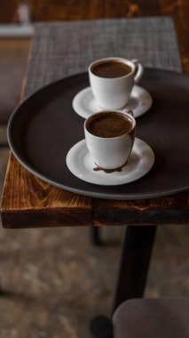 Lokantada tepside duran iki kupa kahve. Koyu renkler, tavan arası tarzı iç mekan. Kimse yok.