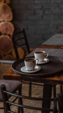 Lokantada tepside duran iki kupa kahve. Koyu renkler, tavan arası tarzı iç mekan. Kimse yok.