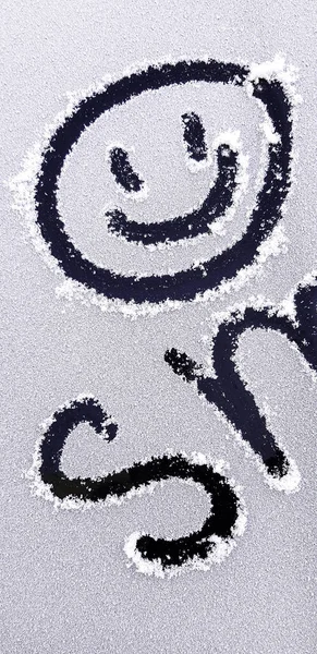 Χαμογελώντας χαμογελώντας με μια επιγραφή ζωγραφισμένη στο χιόνι. — Φωτογραφία Αρχείου