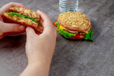 Kadın jambonlu, peynirli, domatesli ve marullu tahıllı sandviç yiyor. Sağlıklı yemek..