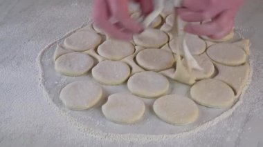 Çiğ hamur hamurundan çörek yapan bir kadın..