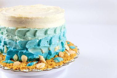Mavi krema ve beyaz arka planda deniz kabuklarıyla süslenmiş deniz keki..