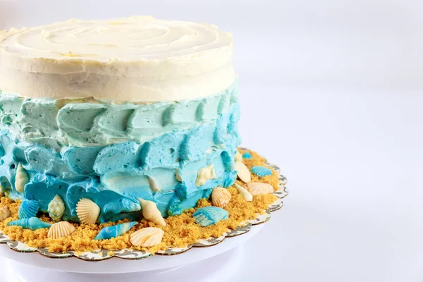 Mavi krema ve beyaz arka planda deniz kabuklarıyla süslenmiş deniz keki..