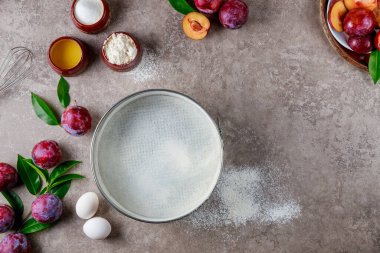 Making plum pie process, ingredients on kitchen table. Copy space.