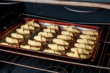 Elektrikli fırında çiğ hilal kurabiyeli fırın tepsisi.