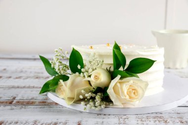 Beyaz arka planda beyaz güller olan güzel düğün pastası.