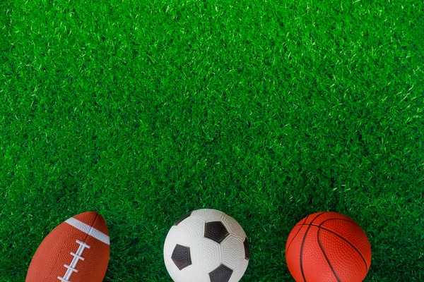 Вид сверху футбольных, баскетбольных и футбольных мячей на зеленом фоне. — стоковое фото