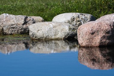 arka plan mavi suya yansıtan kaya ile