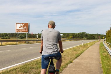 Domtiz, Germany - August 2, 2022: Tourist watching the memorial sign along the former inner-German border in Germany in remembrance of the German devision in East and West Germany