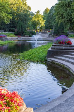Fountains and large classic pond surrounded with flowers in public park Noorderplantsoen in Groningen city in The Netherlands