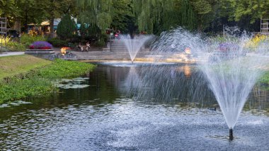 Fountains and large classic pond surrounded with flowers in public park Noorderplantsoen in Groningen city in The Netherlands