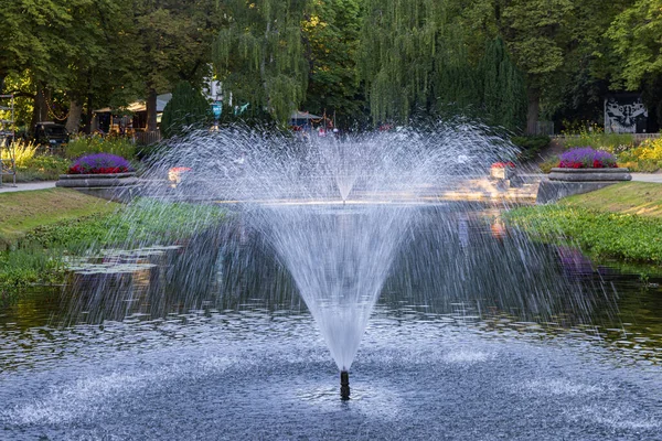 Fountains and large classic pond surrounded with flowers in public park Noorderplantsoen in Groningen city in The Netherlands