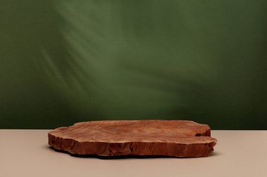 Ürün sunumu için ahşap podyumu olan soyut bir arka plan. Yeşil arka planda palmiye yapraklarının gölgeleri. Boşluğu kopyala.