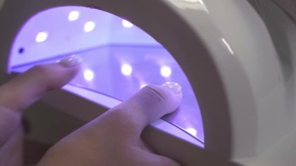 女孩在紫外光灯里擦干指甲，在沙龙里修指甲 — 图库视频影像