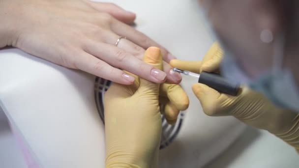 Manikiurzystka w rękawiczkach lateksowych delikatnie nakłada przezroczystą warstwę na paznokcie — Wideo stockowe
