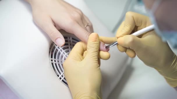 戴着乳胶手套的美容师在钉子上涂上透明的一层 — 图库视频影像