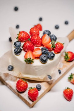 Küçük çilekli bento keki. Beyaz arka planda çilek ve yaban mersiniyle süslenmiş.