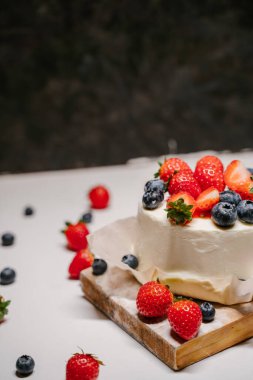 Küçük çilekli bento keki. Beyaz arka planda çilek ve yaban mersiniyle süslenmiş.