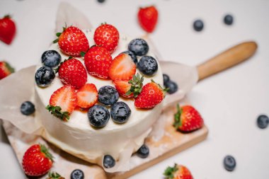 Küçük çilekli bento keki. Beyaz arka planda çilek ve yaban mersiniyle süslenmiş.