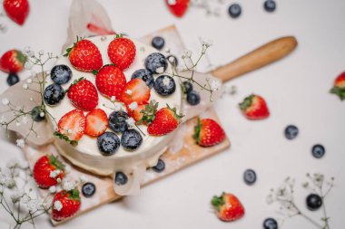 Reklam için beyaz arka planda böğürtlenlerle süslenmiş güzel çilekli pasta.