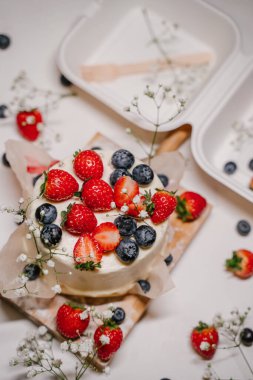 Böğürtlenli Bento keki beyaz bir pakette - bir konteynır tahta bir tahtanın üzerinde duruyor ve beyaz bir arka plan