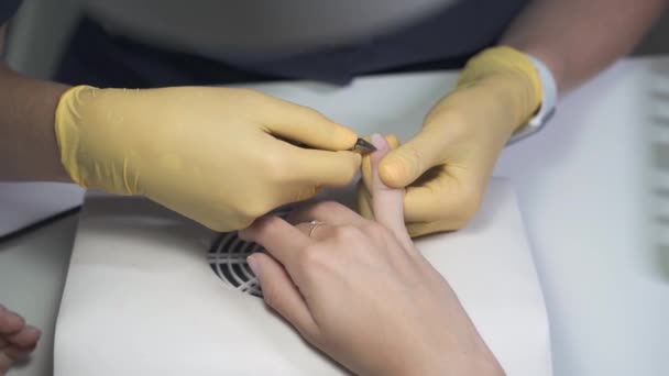 Manikérka v latexových rukavicích s kovovými pinzetami stříhá kůžičku — Stock video