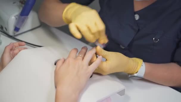 Manikiurzystka w lateksowych rękawiczkach z metalową pęsetą tnie naskórek — Wideo stockowe