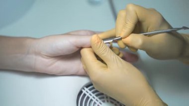 Tırnak törpüsü ustası tırnak derisini budayarak çıkarıyor.