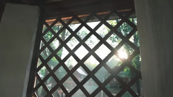 The sunbeams of the sunset penetrate the wooden grid of the gazebo — 图库视频影像