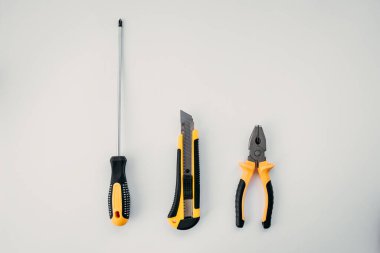 Onarım aletleri, tornavida, kırtasiye bıçağı, beyaz arka planda kerpeten, izole nesneler.