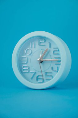 Mavi arkaplanda izole edilmiş klasik tablo saati, dikey resim