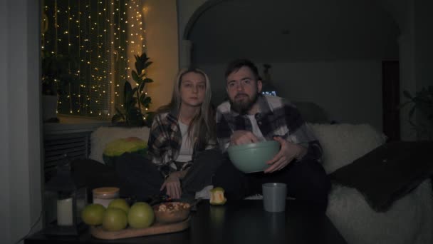 Jovem e mulher assistir filmes com grande interesse, comer batatas fritas — Vídeo de Stock