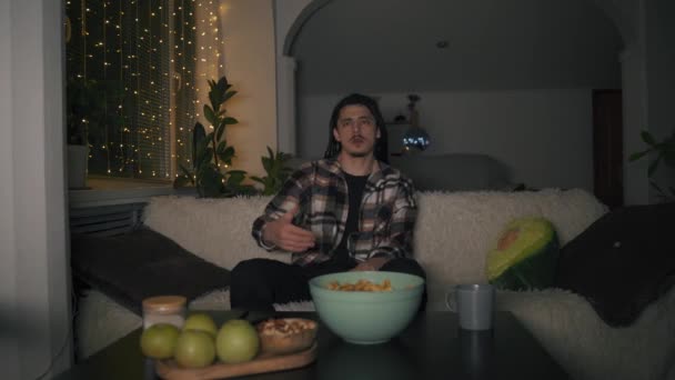 En kille med långa dreadlocks spelar ett tv-spel med koncentration — Stockvideo