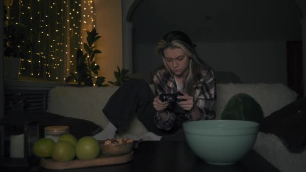 Красива молода дівчина емоційно грає в ігрову консоль, зосереджуючись на завданні — стокове відео
