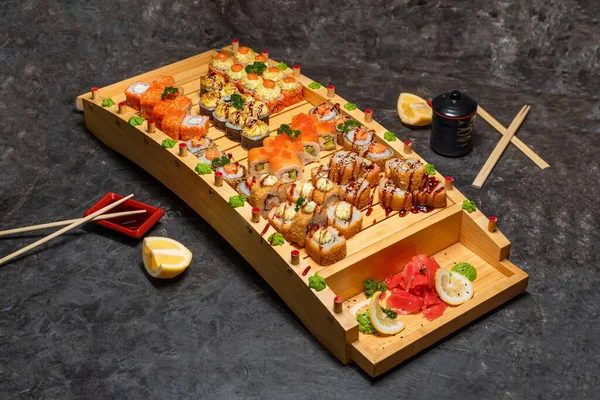 大盘日本卷和寿司，黑色背景，木制托盘 — 图库照片