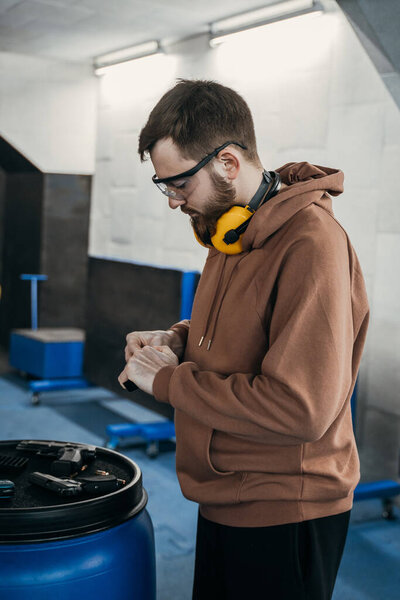 Человек перезаряжает оружие перед тем, как выстрелить в цель. Наполняю магазин пистолетов. Спортивные развлечения